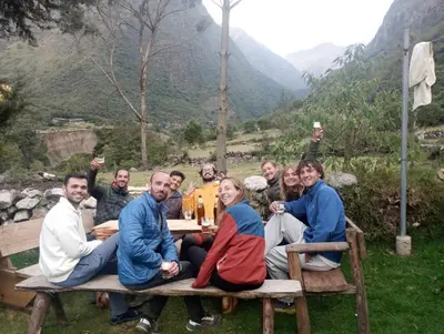 a group of people sitting around a picnic table at Hostel el molle capulichayoc in Santa Teresa