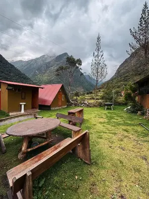 a picnic table and benches in a field with mountains at Hostel el molle capulichayoc in Santa Teresa