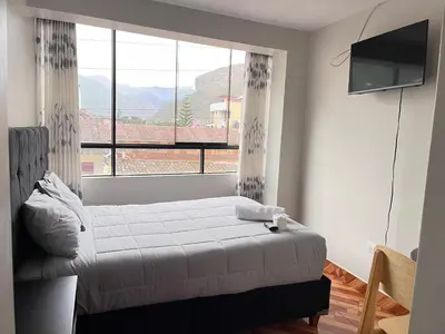 a bedroom with a bed and a large window at Hostal El Mariscal in Urubamba