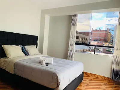 a bedroom with a bed and a large window at Hostal El Mariscal in Urubamba