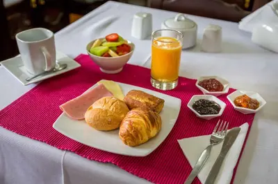 a table with a plate of breakfast food and a glass of orange juice at Illa Hotel in Cusco