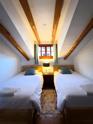 two beds in a room with a window at Illa Hotel in Cusco