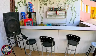 a bar with black chairs and a counter at Allawaska Hostel & Camping in Laguna Huacachina