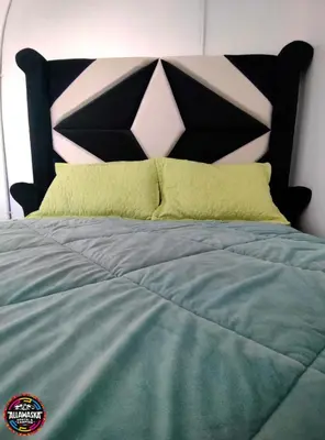 a bed with a black headboard and yellow pillows at Allawaska Hostel & Camping in Laguna Huacachina