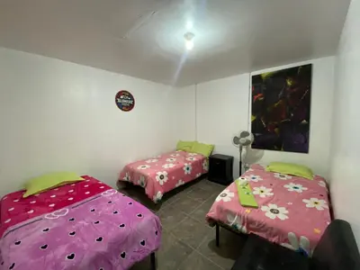 two beds in a room with pink sheets at Allawaska Hostel & Camping in Laguna Huacachina