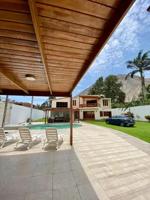 a patio with chairs and a house and a car at Casa Vaí Cieneguilla with a pool in Cieneguilla