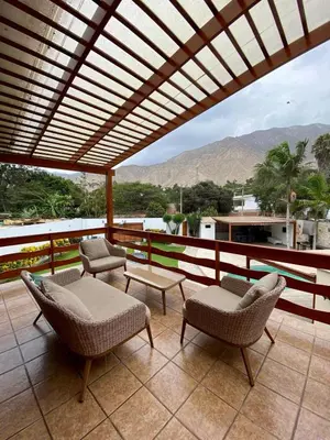 a patio with chairs and a table and mountains at Casa Vaí Cieneguilla with a pool in Cieneguilla