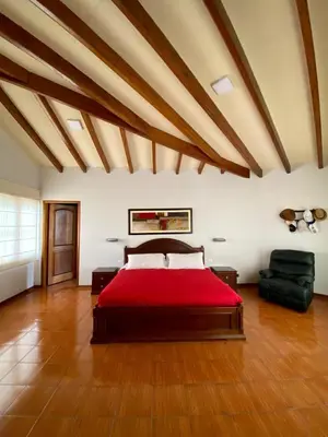a bedroom with a large bed with a red blanket at Casa Vaí Cieneguilla with a pool in Cieneguilla