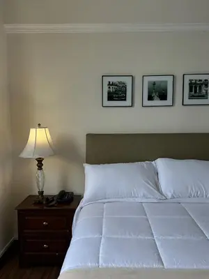 a bed with white sheets and a lamp on a night stand at Kontiki Miraflores in Lima