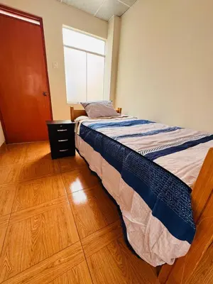 a bedroom with a bed with a wooden floor and a window at La CASITA in Cusco