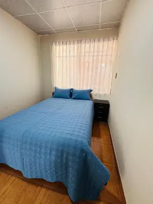 a bedroom with a bed with blue sheets and a window at La CASITA in Cusco