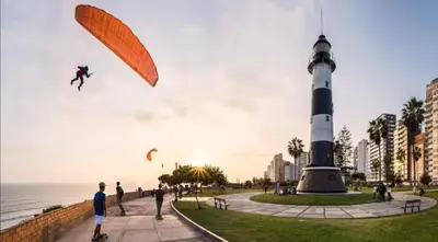 a group of people flying kites near a lighthouse at DivarAparts#1 in Lima