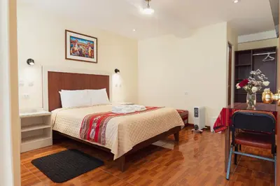 a bedroom with a bed and a table and a chair at Hotel Casa Suite Inka in Ollantaytambo