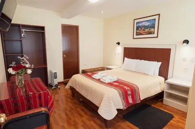 a hotel room with a bed and a vase of flowers at Hotel Casa Suite Inka in Ollantaytambo