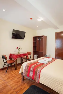 a bedroom with a bed and a table and a desk at Hotel Casa Suite Inka in Ollantaytambo