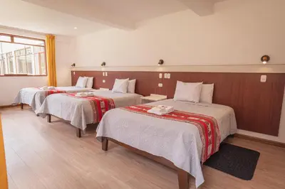 a hotel room with three beds and a window at Hotel Casa Suite Inka in Ollantaytambo