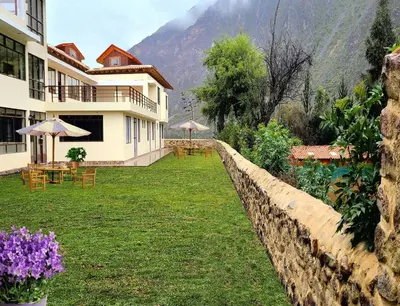 a building with a yard with tables and umbrellas at Hotel Casa Suite Inka in Ollantaytambo
