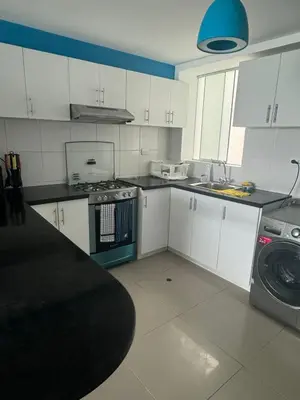 a kitchen with white cabinets and a washing machine at Beautiful apartment with an ocean view in San Bartolo