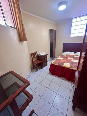 a bedroom with a bed and a table and a window at Hs San Cristobal in Ayacucho