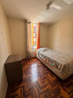 a bedroom with a bed and a wooden floor at Departamento in Lima