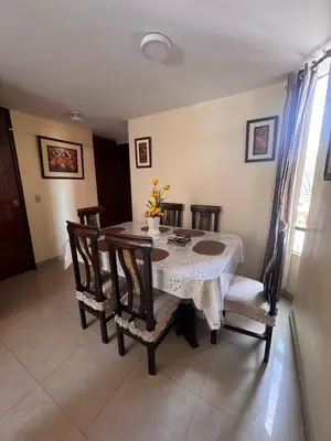 a dining room with a table with chairs and a white table and chairsktop at Departamento in Lima