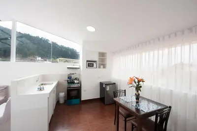 a white kitchen with a table and a kitchen with a window at Carmen's House in Cusco