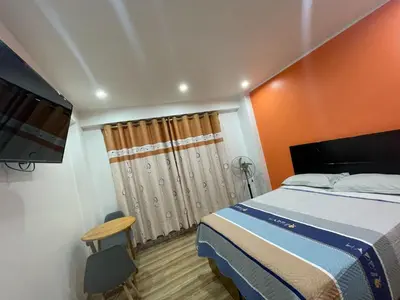 a bedroom with a bed with an orange wall at Hostal los Ficus in Ica