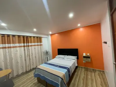 a bedroom with a bed and an orange wall at Hostal los Ficus in Ica