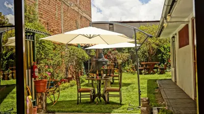 a table with an umbrella in a garden at Illas Inn in Cusco