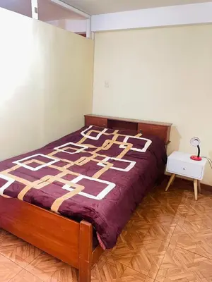 a bedroom with a bed with a purple blanket at Departamento amplio y cómodo a 15 minutos del aeropuerto in Lima
