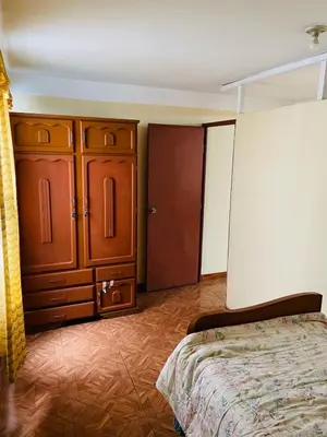 a bedroom with a bed and a wooden cabinet at Departamento amplio y cómodo a 15 minutos del aeropuerto in Lima
