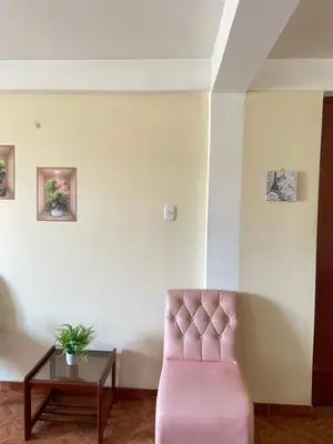 a pink chair in a room with a table at Departamento amplio y cómodo a 15 minutos del aeropuerto in Lima