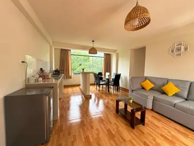 a living room with a gray couch and a kitchen at Departamento Maranura Quillabamba in Maranura