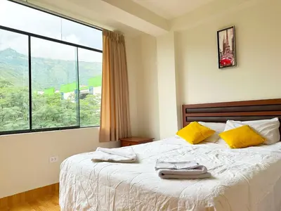 a bedroom with a bed with yellow pillows and a window at Departamento Maranura Quillabamba in Maranura