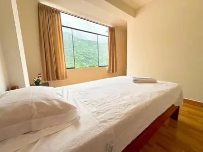 a bedroom with a large bed with a window at Departamento Maranura Quillabamba in Maranura
