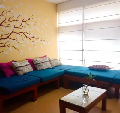 a living room with a blue couch and a tree mural at Miraflores Larco in Lima