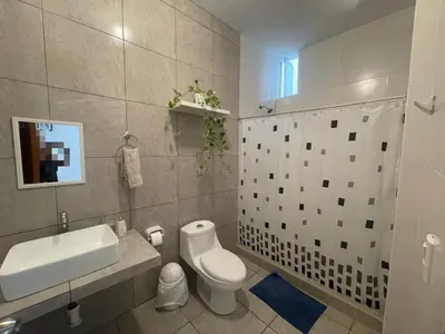 a bathroom with a white toilet and a sink at Refugio en Cieneguilla relax, piscina y sol in Cieneguilla