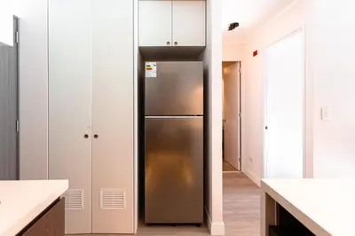 a stainless steel refrigerator in a kitchen with white cabinets at Brand-new designer apt - Pool in Miraflores in Lima