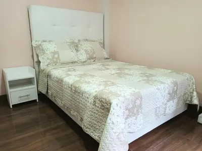 a small bedroom with a bed and a night stand at Katty's apartment - Las Malvas in Lima