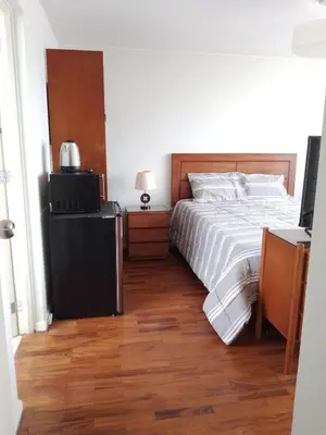 a bedroom with a large bed and a wooden floor at Miraflores, Lima, habitación independiente in San Antonio