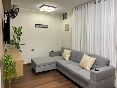 a living room with a gray couch in front of a window at El Encanto Espacio Calido A warm space in Los Olivos in Lima