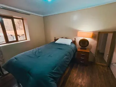 a bedroom with a bed and a lamp and a window at Casa Aguilar in Urubamba