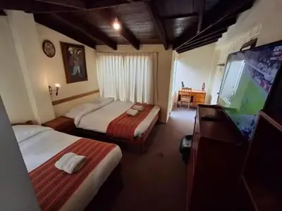 a hotel room with two beds and a flat screen tv at Andean Dreams 1 in Cusco
