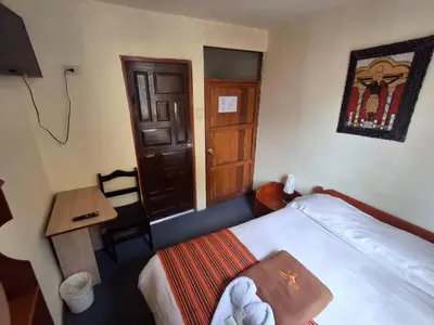 a bedroom with a bed and a table and a door at Andean Dreams 1 in Cusco