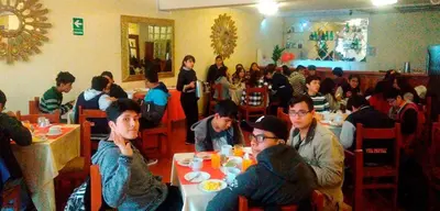 a group of people sitting at tables in a restaurant at Hotel WhiteHouse in Cusco