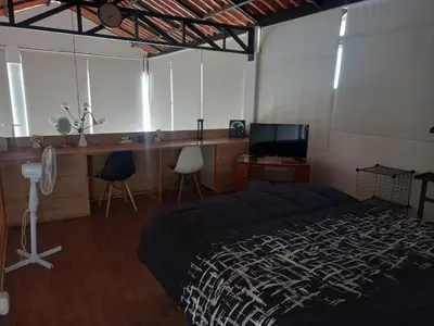 a bedroom with a bed and a desk and a tv at Nice country house with pool and beautiful view in Huarochirí