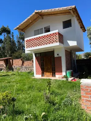 a small house with a green lawn in front of it at Casa de Marguito in Urubamba