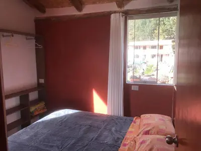 a bedroom with a bed next to a window at Casa de Marguito in Urubamba