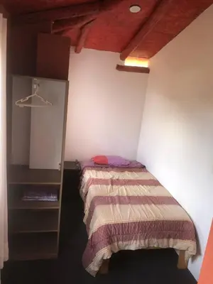 a small bedroom with a bed and a shelf at Casa de Marguito in Urubamba