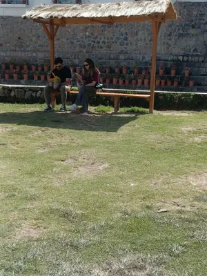 two people sitting on a bench under a gazebo at 7 Borreguitos GUESTHOUSE in Cusco